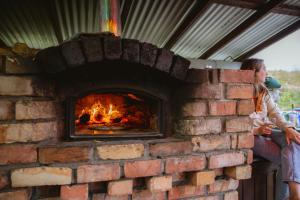 a woman sitting next to a brick oven at Mayo Glamping in Castlebar