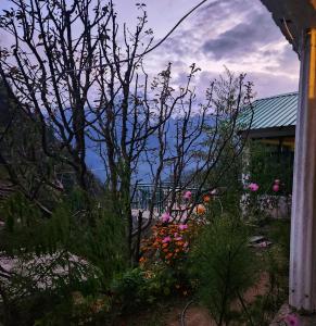 a garden with flowers in front of a house at L'Ashrum Cafe & Inn in Tosh