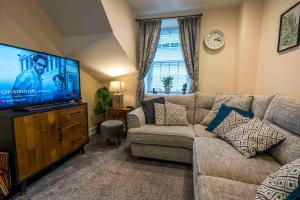 a living room with a couch and a flat screen tv at Cosy Cottage in Central Kendal with Parking! in Kendal