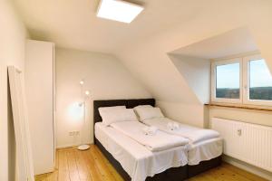 Schlafzimmer mit einem Bett mit weißer Bettwäsche und einem Fenster in der Unterkunft Charmante Dachgeschosswohnung in Pforzheim