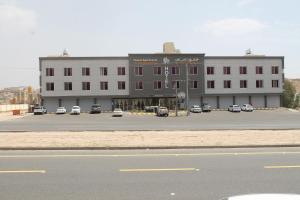 un gran edificio con coches estacionados en un estacionamiento en داماس للأجنحة الفندقية Damas Hotel Suites, en Al Maraghah