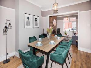 a dining room with a table and green chairs at Pass the Keys Beautifully refurbished home close to City in Manchester