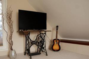 a tv sitting on a table next to a guitar at Originálne bývanie v starej sýpke z roku 1828. 