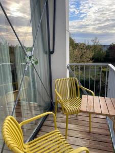 2 gelbe Stühle und ein Tisch auf einer Veranda in der Unterkunft Charmant Studio avec parking - Confort Moderne in Bourges