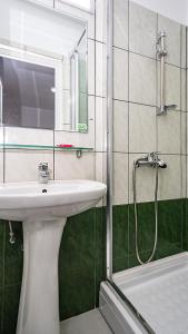 uma casa de banho com um lavatório e um chuveiro com um espelho. em Hotel La Platouri em Voluntari