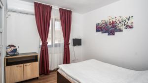 um quarto com uma cama e uma janela com cortinas vermelhas em Hotel La Platouri em Voluntari