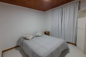 a white bedroom with a bed and a window at Cabañas La Estación in Chascomús +13 photos