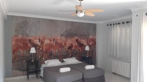 a bedroom with a painting of birds on the wall at flamingos rio in Montijo