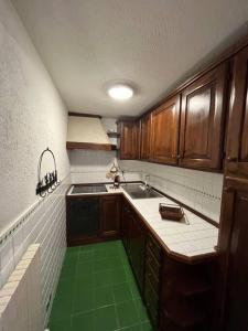 a kitchen with wooden cabinets and a green floor at refuge du skieur cir 0051 in Courmayeur