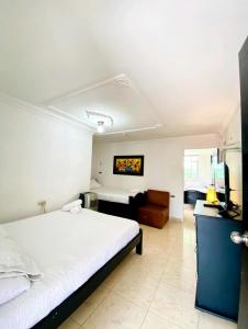 1 dormitorio con 1 cama blanca grande y 1 sofá en Hotel West California, en Armenia