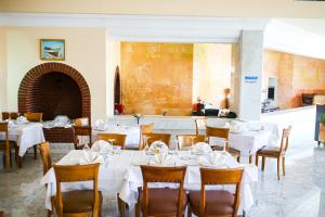 a dining room with white tables and wooden chairs at Mahdia Palace Thalasso in Mahdia