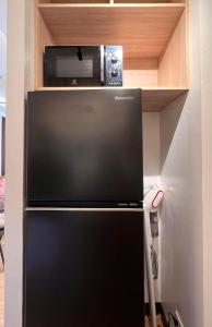 a black refrigerator with a microwave on top of it at AJ’s Cozy Condo Davao in Davao City