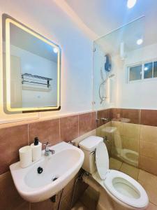 ein Badezimmer mit einem Waschbecken, einem WC und einem Spiegel in der Unterkunft AJ’s Cozy Condo Davao in Davao City