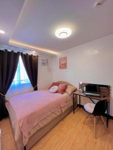 a bedroom with a bed and a desk with a computer at Adi Hideaway Staycation at Arezzo Place Davao in Davao City