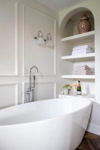 a white bath tub in a bathroom with white shelves at Riverbank house - Cookham in Cookham