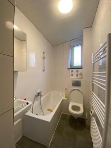 ein weißes Bad mit einer Badewanne und einem WC in der Unterkunft Annie´s Appartements in Mannheim