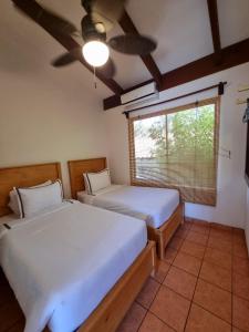 two beds in a room with a ceiling fan at Casa de Encanto Tropical Villa in Playa Hermosa