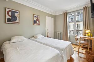 um quarto com 2 camas, uma mesa e uma janela em Hôtel Juliette em Paris