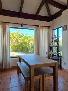 uma sala de jantar com uma mesa e uma grande janela em Casa de Encanto Tropical Villa em Playa Hermosa