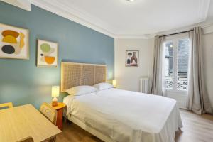 Un dormitorio con una gran cama blanca y una mesa en Hôtel Juliette en París