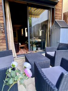 een patio met rieten stoelen en een vaas met bloemen bij Maison eco-responsable proche de Paris in Villennes-sur-Seine