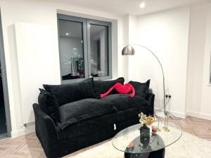 a black couch in a living room with a glass table at Stunning property with London city and river views in London