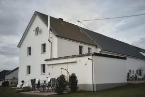 a white house with tables and chairs in front of it at Wohlfühl-Ferienhaus Eifel-Landurlaub mit Herz in Dahlem