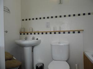 a white bathroom with a toilet and a sink at Granary Cottages in Swindon