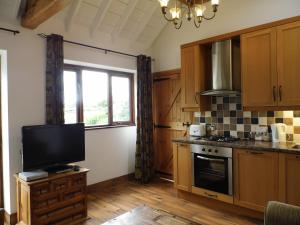 a kitchen with wooden cabinets and a tv in it at Granary Cottages in Swindon