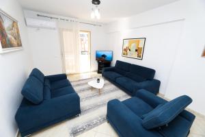 ein Wohnzimmer mit 2 blauen Sofas und einem TV in der Unterkunft Noa Apartments in Vlorë