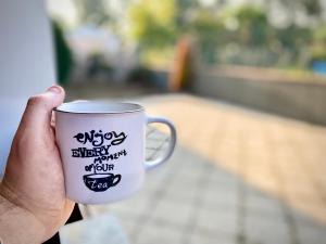 una mano sosteniendo una taza de café con escritura. en Malpensa Home Milan Lakes, en Case Nuove