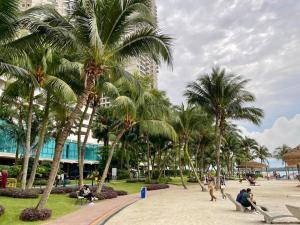 une plage avec des palmiers et des personnes assises sur des bancs dans l'établissement Poolside Haven: 2BR Garden Oasis, à Johor Bahru