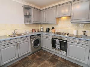 cocina con armarios blancos y lavadora en The Croft, North Staffordshire, en Stoke on Trent