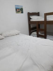 a white bed in a room with a table at Casa com estacionamento coberto, localizada em Vila Sahy in São Sebastião