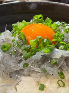 a bowl of onions and green onions with an orange object at ハセノ島　Hotel　Cottage in Kamakura