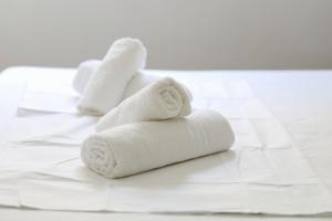 einen Haufen weißer Handtücher auf einem Bett in der Unterkunft Noa Apartments in Vlorë
