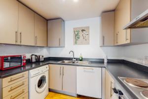 een keuken met een wastafel en een wasmachine bij Appealing 2 Bedroom apartment in Bethnal Green in Londen