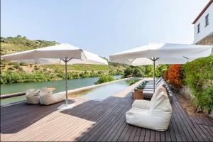 2 sillas blancas y sombrillas junto a una piscina en Quinta de Merouço - Casa do Rio, en Cotas