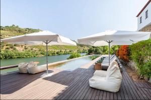 two white chairs and umbrellas next to a swimming pool at Quinta de Merouço - Casa do Rio in Cotas