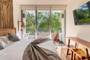 ein Schlafzimmer mit Bett, Schreibtisch und Fenster in der Unterkunft NHOA 209B Lux 1BR Condo Pool View in Aldea Zama in Tulum + 25 Fotos
