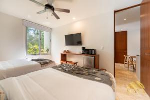 ein Schlafzimmer mit zwei Betten und einem Flachbildfernseher in der Unterkunft NHOA 209A Lux 2BR Condo Pool View in Aldea Zama in Tulum + 31 Fotos