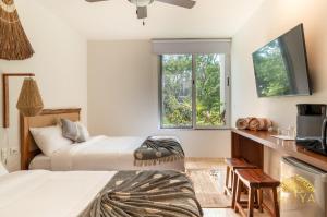ein Schlafzimmer mit zwei Betten und einem Flachbildfernseher in der Unterkunft NHOA 209A Lux 2BR Condo Pool View in Aldea Zama in Tulum