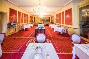 a restaurant with tables and chairs and a chandelier at Mercure Moulins Centre Hôtel de Paris in Moulins