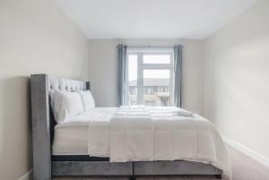 a white bedroom with a large bed with a window at Niagara Elite Enclave in Niagara Falls