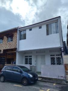 a blue car parked in front of a white house at WW Hostel 22A Private Shower in George Town