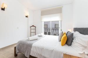 ein weißes Schlafzimmer mit einem großen Bett und gelben Kissen in der Unterkunft Casa Gaivota by Algarve Golden Properties in Lagos