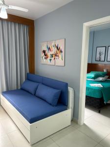 a room with a blue couch in a room with a bed at Boulevard Riviera Flat - VISTA MAR E CLUBE in Riviera de São Lourenço