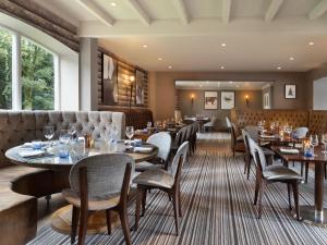 um restaurante com mesas e cadeiras e um sofá em Delta Hotels by Marriott Worsley Park Country Club em Worsley