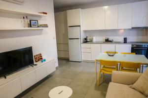 eine Küche mit weißen Schränken und einem Tisch mit einem TV in der Unterkunft Luxury Stay in İncirli
