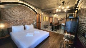 - une chambre avec un lit blanc et un mur en briques dans l'établissement House of Machine Boutique Hotel, à Bangkok